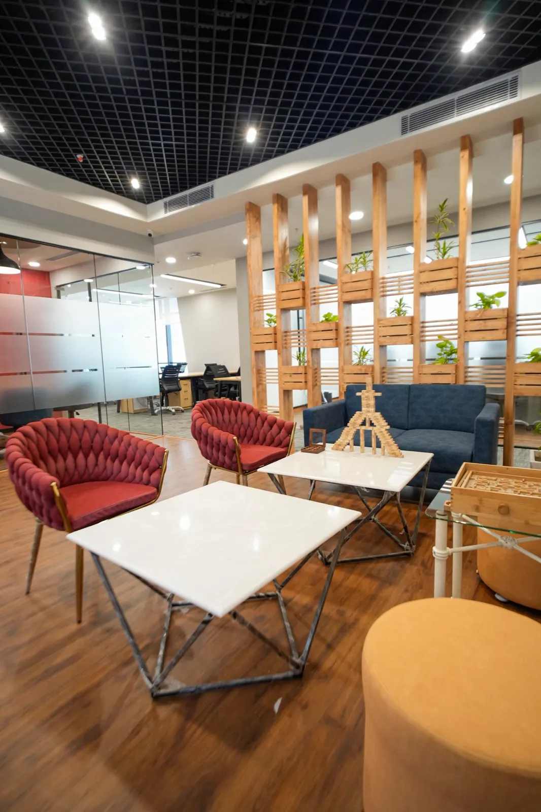 Navy tufted leather Chesterfield sofa flanked by wood side tables with gold decor on patterned carpet — AIHP managed office, Gurgaon