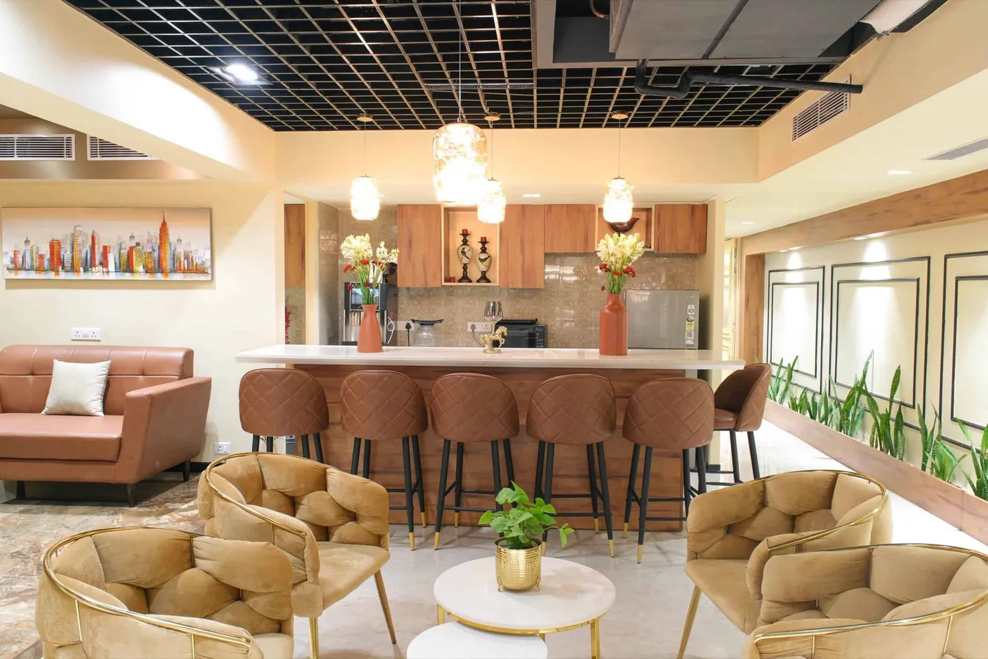 Cafe lounge with a stone-top bar, leather stools, gold velvet tub chairs and pendant lights — AIHP managed office, Gurgaon