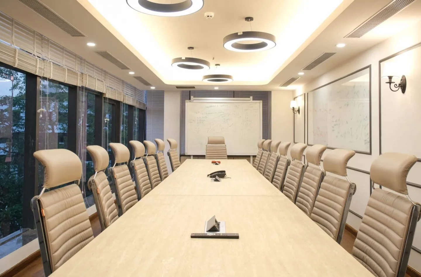 Twenty-seat travertine table with beige ribbed chairs, ring pendants and a whiteboard — AIHP managed office, Gurgaon