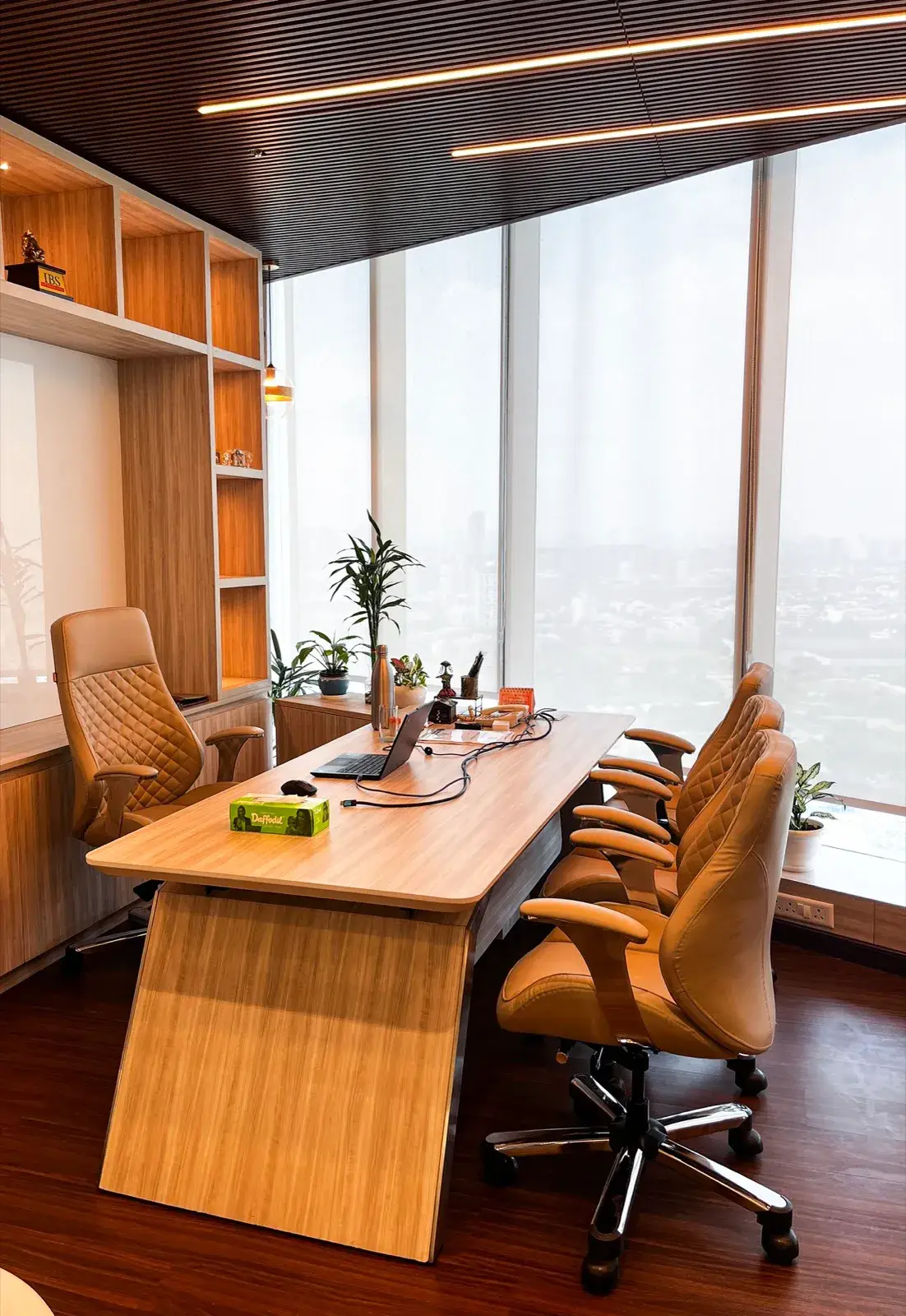 Spacious high-floor cabin with wood desk, tan leather chairs and floor windows over a city view — AIHP managed office, Gurgaon